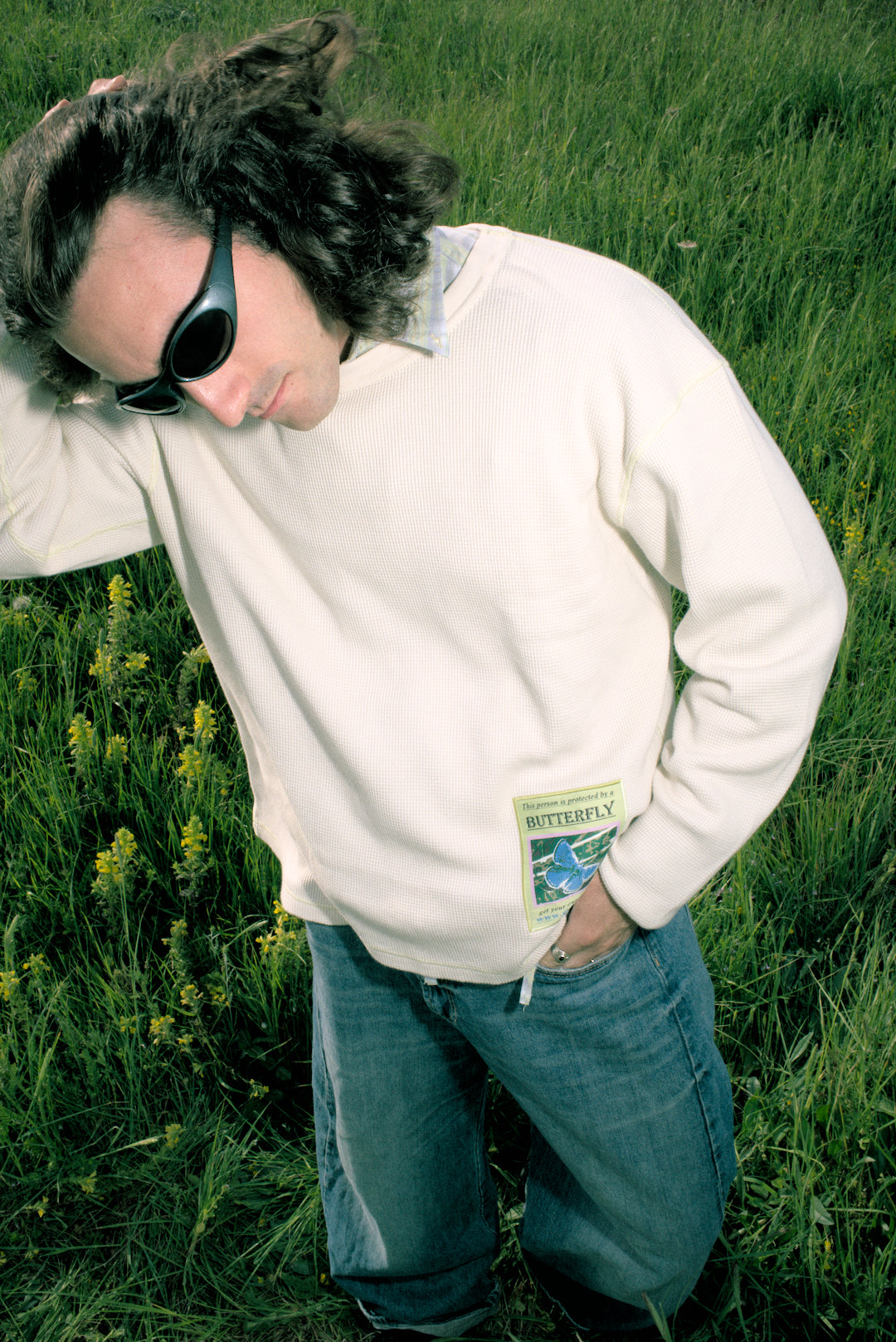 Person wearing a white sweatshirt with a logo in a grassy field