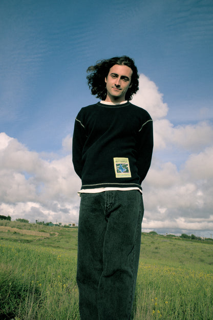 Person standing in a field with a blue sky and clouds in the background